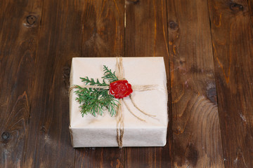 gift wrapped in kraft paper, tied with string and glued wax seal. Lying on the table.