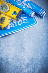 Blue construction plans level tape measure on metallic backgroun