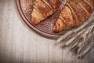 Ripe wheat rye ears croissants copper tray on wooden board