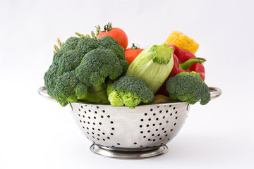 Various vegetables in a metal colander. Isolated photo
