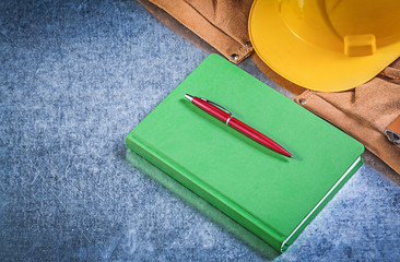 Tool belt building helmet notepad pen on metallic background con