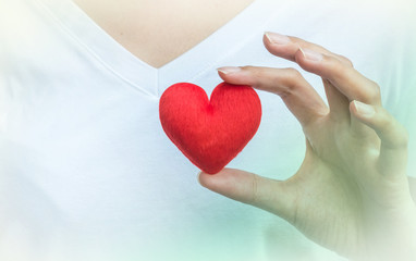 Closeup red heart shape fabric on woman hand