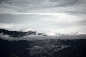 Naklejka na ściany i meble Wolken ziehen über die Berge / Wolken und Nebel ziehen über die Gipfel und Bergrücken eines Gebirges beziehungsweise Bergkette.
