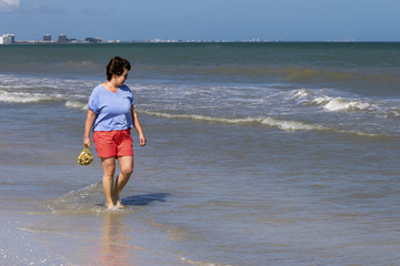 Woman walking on beach collecting seashells