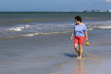 Woman walking on beach collecting seashells