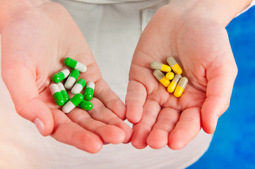 Medical pills green, yellow, grey in human's hands