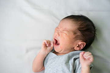 Asian newborn baby lying and crying in his bed