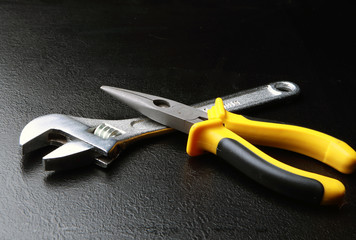 гаечный ключ и клещи на черном фоне