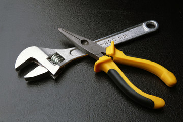 гаечный ключ и клещи на черном фоне