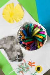 Set of bright colorful pens in a white pot with a child's drawing. Creativity for kids. Colors of childhood