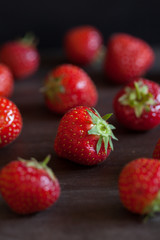 Fresh ripe strawberries scattered on to wooden worktop. Focus on one strawberry