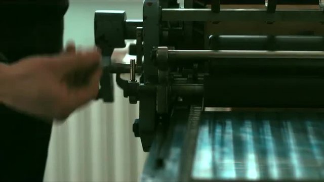 Caucasian male preparing a vintage letterpress machine for printing. Close up 4k 60 FPS. Shot with Blackmagic URSA Mini