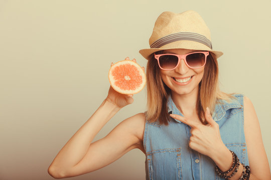 Happy woman in hat and sunglasses with grapefruit.