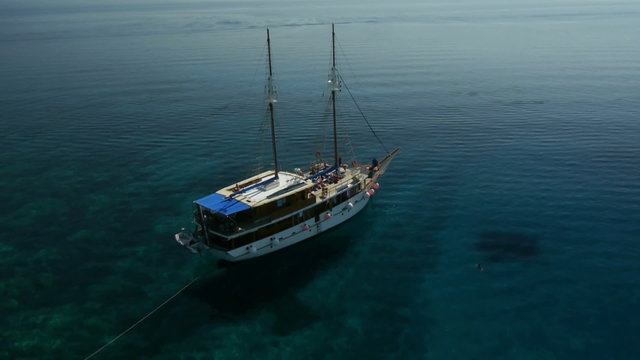 Aerial view of docked Wooden boat in the bay with beautiful clear blue water.
