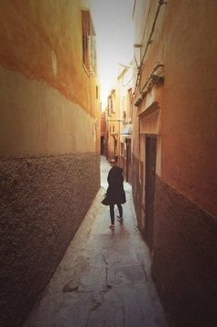 Young woman walks alone in an alley in the Marrakech Medina 