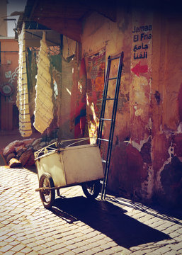 Ladder and cart against a wall in Marrakech at sunset