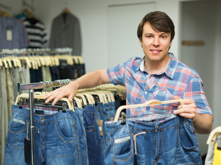 Man choosing blue jeans at the shop.