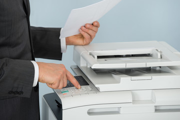 Close-up Of Businessman Pressing Printer's Button In Office