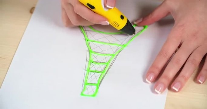 Close-up high angle of amateur designer making green plastic Eiffel tower model with 3D printing pen 