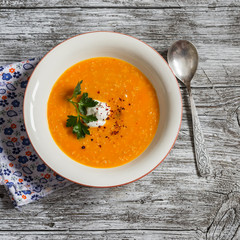 Healthy quinoa carrot soup on rustic light wooden board. Delicious vegetarian food