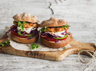 Homemade  fish burger on a light rustic wooden board