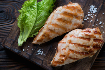Close-up of grilled chicken breast filets with green salad