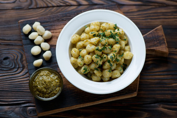 Boiled gnocchi with pesto sauce in a rustic wooden setting