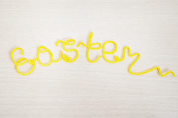 The inscription of the wire "Easter" on  light wooden background