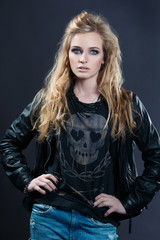 Fototapeta na wymiar Portrait of a charismatic female rocker in leather jacket on a gray background