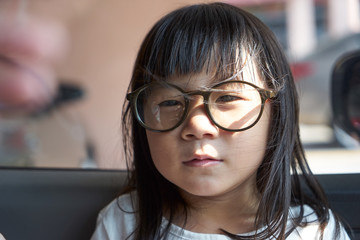 Adorable serious little girl and big funny glasses on her face. Toned image with shallow depth of field