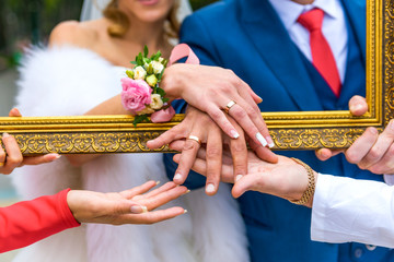 Groom and bride show their rings through the frame