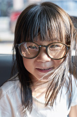 Adorable happy little girl and big funny glasses on her face. Toned image with shallow depth of field