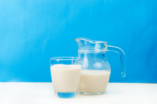 Milk in a glass jug and glass on wooden background