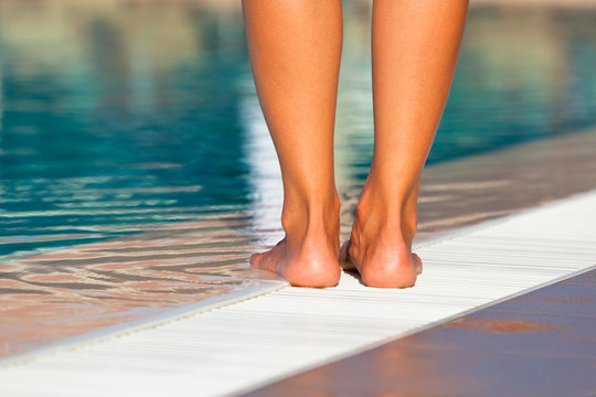 Woman legs standing on the edge of swimming pool