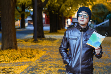 Fototapeta premium An asain man in a brown jacket walks in a street