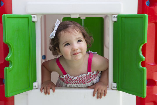 Little Girl Smiling Through The Window Of Kids Playhouse