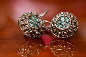 Silver earrings sitting on shiny surface