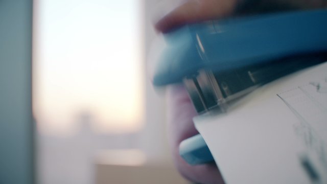 A hand using a stapler in an office