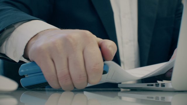 businessman uses stapler and notebook