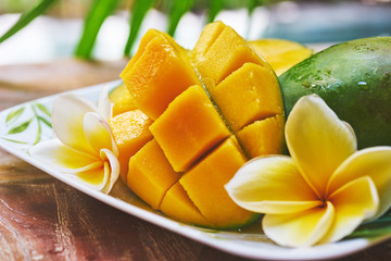 Fresh mango on a wooden tabel with tropical background. Soft focus.