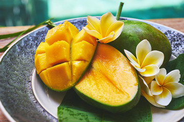 Fresh mango on a wooden tabel with tropical background. Soft focus.