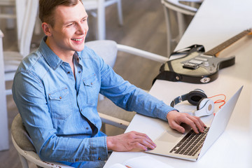 Cheerful guy using laptop. 