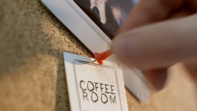 hand pins information about coffee room to the cork Board with pushpins
