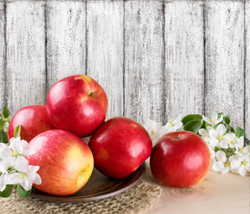 Red apples with decorated apple flowers on the background wooden wall in the style Shabby Chic