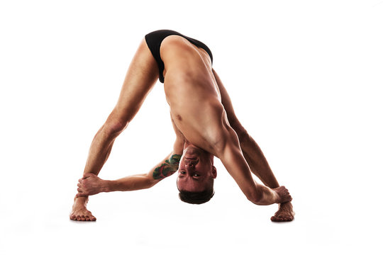 young strong man doing yoga and gymnastics, deep twisting