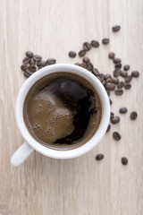 Coffee cup with roasted coffee beans on wooden background.