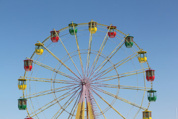 Ferris wheel with color cabins against the blue sky