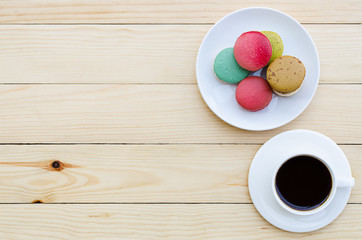 cup of coffee and macaroons on wooden table, top view