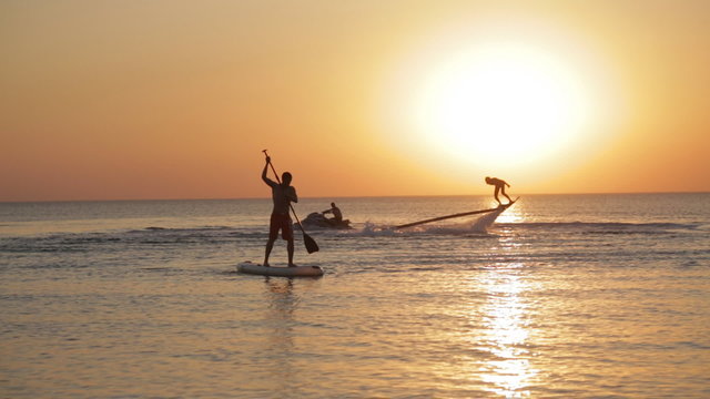 Man Hovers On A Hoverboard Over The Water On The Sunset Background