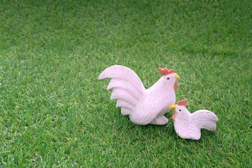 Still life of Sweet ceramic couple of hen and cock chicken doll on green grass/Sweet ceramic chicken couple on green grass